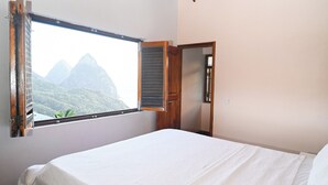A bedroom with a bed, a window with a view of mountains, and a wooden door. - Piton Villa Deck.. Million View of Majestic Pitons (Soufrière)