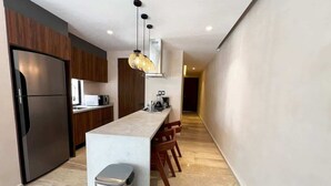 Una cocina moderna con una isla central, armarios de madera y un refrigerador de acero inoxidable.