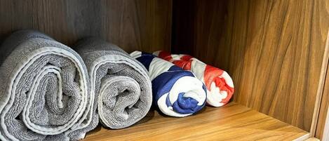 A wooden shelf with rolled towels in various colors.