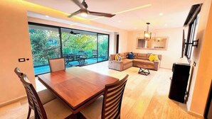 Un espacio habitable amplio con una mesa de comedor de madera, un sofá y un ventilador de techo.
