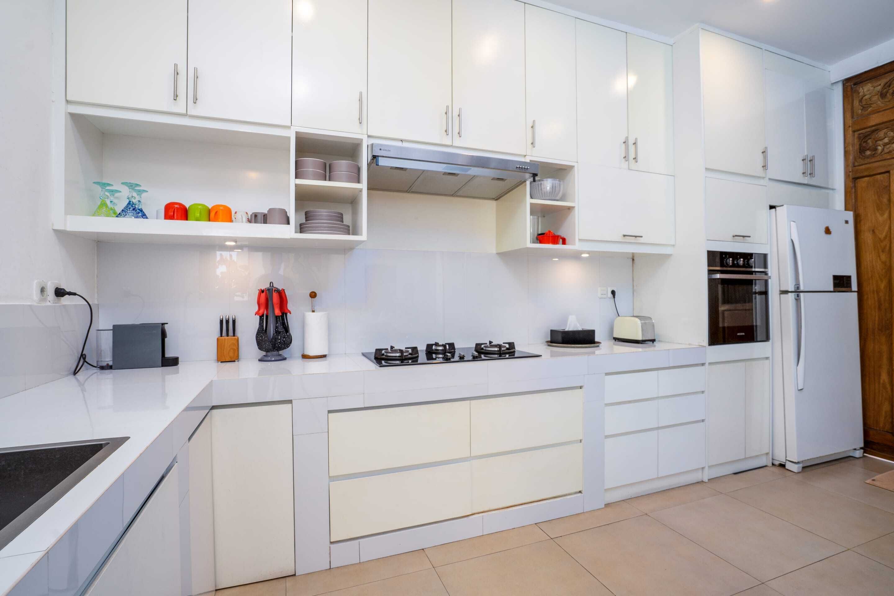 Une cuisine moderne avec des meubles blancs, une cuisinière à gaz, un four et un réfrigérateur.