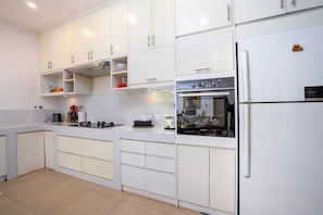 Una cocina moderna con armarios blancos, horno integrado y refrigerador.