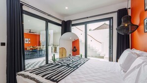 A modern bedroom with a large bed, a view of the outdoor area, and a staircase leading to an upper level. - Villa Tulum (Canggu)