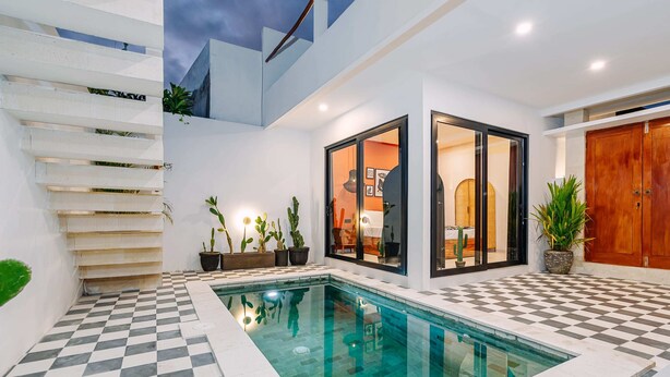 A modern pool area with a checkered floor, a glass-enclosed room, and a wooden door. - Villa Tulum (Canggu)