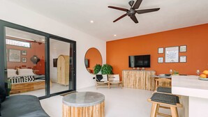 A modern living room with a sofa, a round coffee table, and a bar area with stools. - Villa Tulum (Canggu)