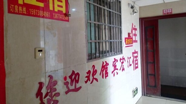 A hotel interior with a red and white sign indicating room availability and contact numbers. - Xinhua Huihong Hotel (Xinhua)