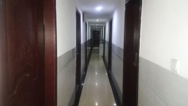 A long, narrow hallway with dark wooden doors on both sides and a shiny tiled floor. - Xinhua Huihong Hotel (Xinhua)