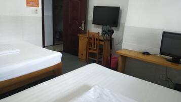 A hotel room with two beds, a desk with a chair, a television, and a door.