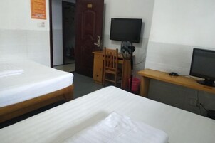 Quarto de hotel com duas camas, uma escrivaninha com cadeira, uma televisão e uma porta.