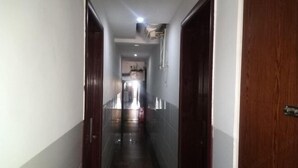A narrow hallway with a wooden door on the right and a white door on the left. - Xinhua Huihong Hotel (Xinhua)