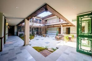 A spacious indoor courtyard with a wooden ceiling structure, a green gate, and a seating area with outdoor furniture. - Wuxi Nianhua Bay Polomydo Hotel, (Wuxi)