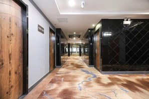 A hotel corridor with wooden doors, a patterned carpet, and a security gate. - Qingmu Hotel Changzhou Founder Building (Changzhou)