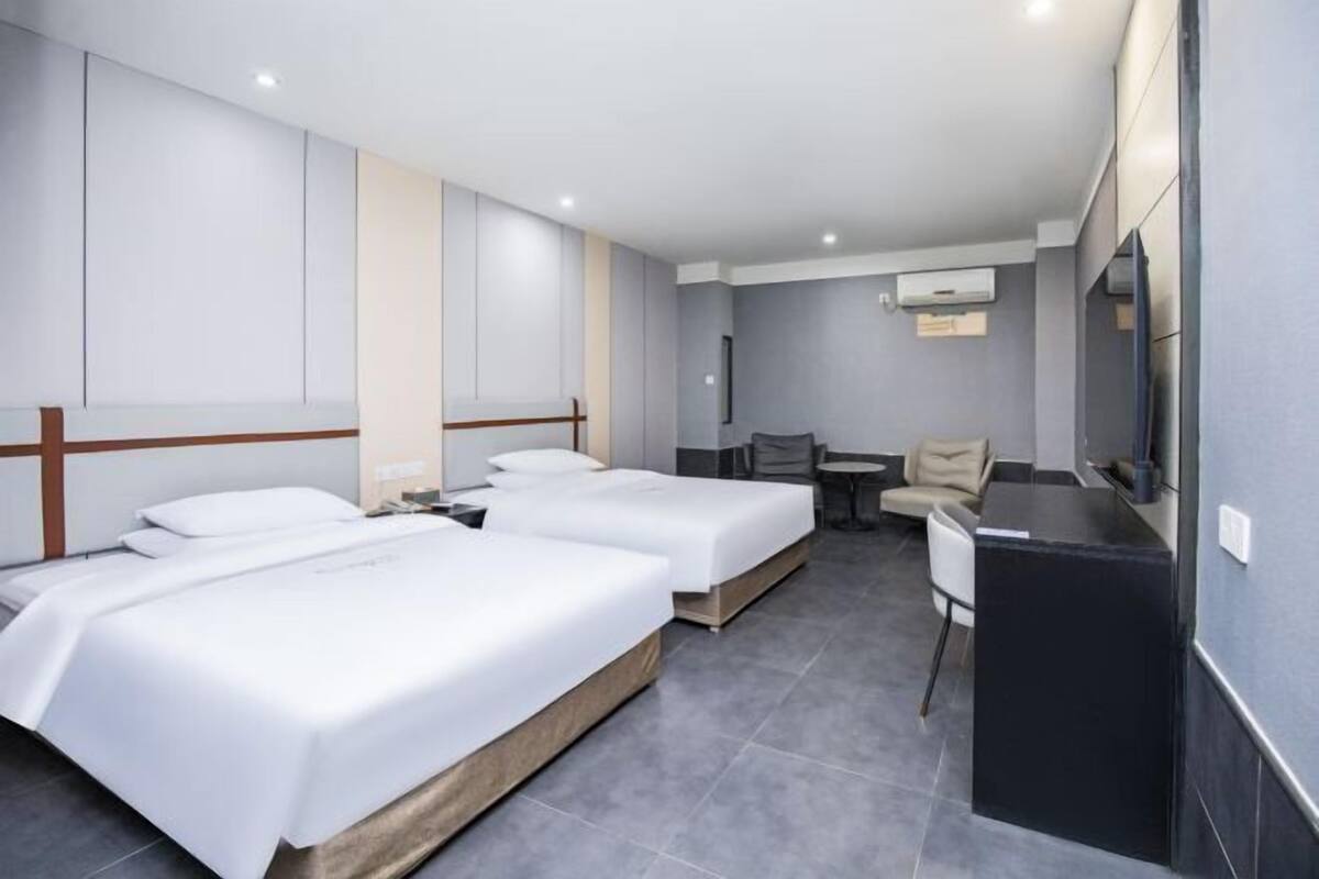 A hotel room with two beds, a desk, and a chair.