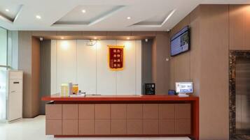 A reception desk with a digital screen, a red sign, and a wall-mounted television.