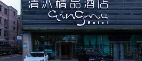 A hotel entrance with a sign that reads "Gingmu Hotel" in both Chinese and English.