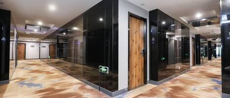A hotel corridor with glass doors, a wooden door, and a carpeted floor.