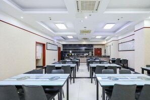 A conference room with multiple tables and chairs, a kitchenette in the background, and a ceiling with recessed lighting. - Qingmu Hotel Changzhou Founder Building (Changzhou)