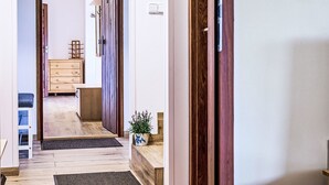 A hallway with a wooden door, a small plant, and a white wall with two light switches.
