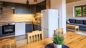 A modern kitchen with dark cabinets, a white refrigerator, and a dining area with a wooden table and chairs.