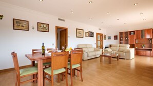 A spacious living area with a dining table, chairs, a sofa, and a cabinet.