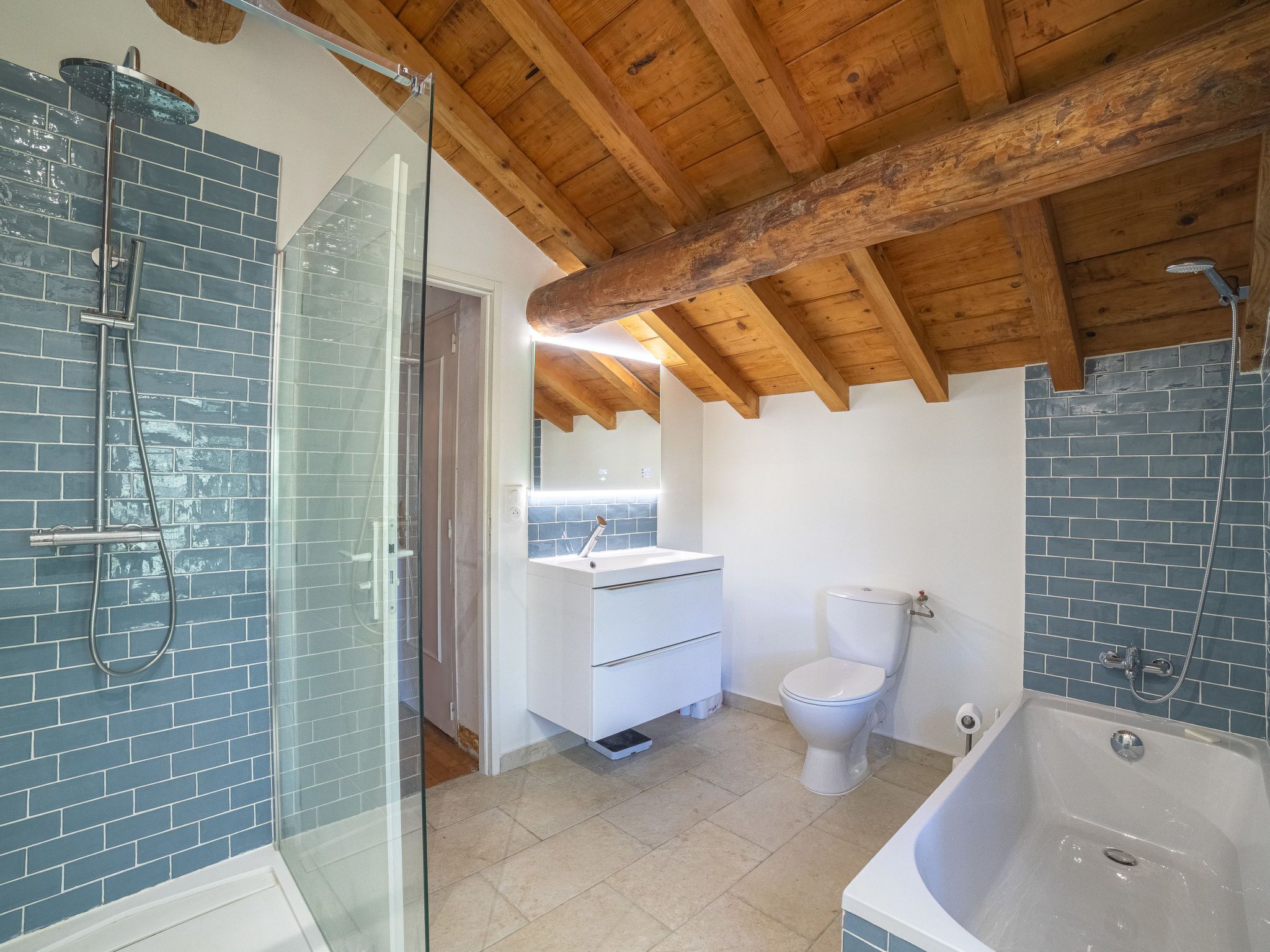 A bathroom with a glass shower enclosure, a white toilet, a bathtub, and a sink with a mirror.