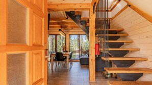 Un intérieur en bois avec un escalier, un coin repas et de grandes fenêtres.