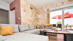 Ein modernes Wohnzimmer mit einem grauen Ecksofa, einem Holztisch und einer Steinwand.