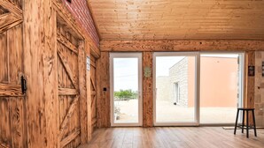 Ein Zimmer mit Holzwänden und Holzboden, große Schiebeglasfenster zu einem Außenbereich.