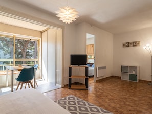 Relax in this cozy living space with a large window offering a view of the surrounding trees, a flat-screen TV, and a comfortable seating area.