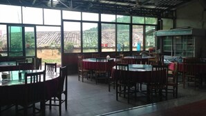 Un restaurante con ventanas amplias, mesas y sillas de madera.