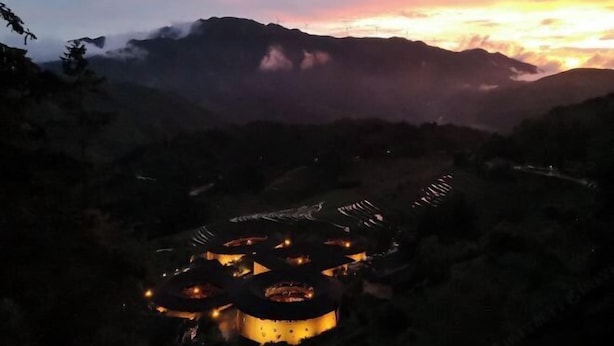 Un complejo de edificios circulares con varias construcciones, rodeado de un paisaje montañoso.