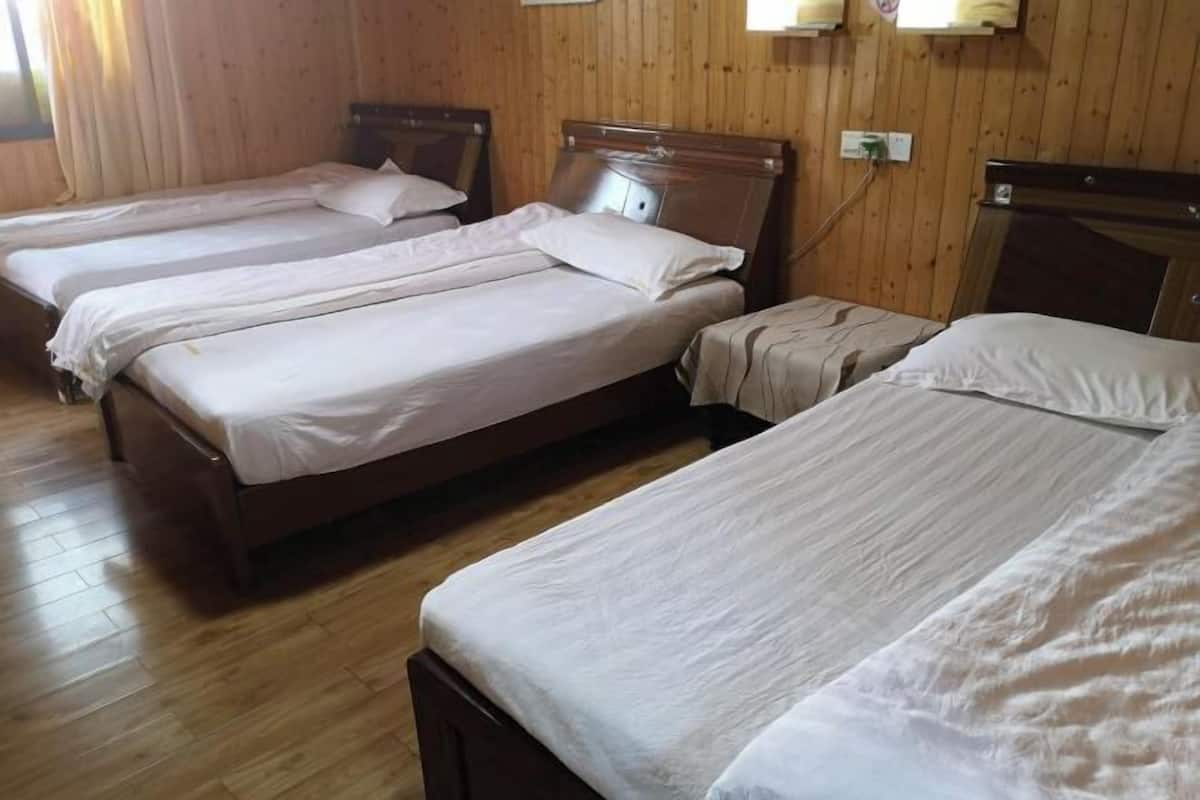 A room with four wooden beds arranged in a row, each with a wooden headboard and white bedding.