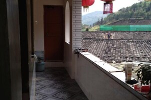 Un balcón con vistas a un edificio tradicional y montañas.