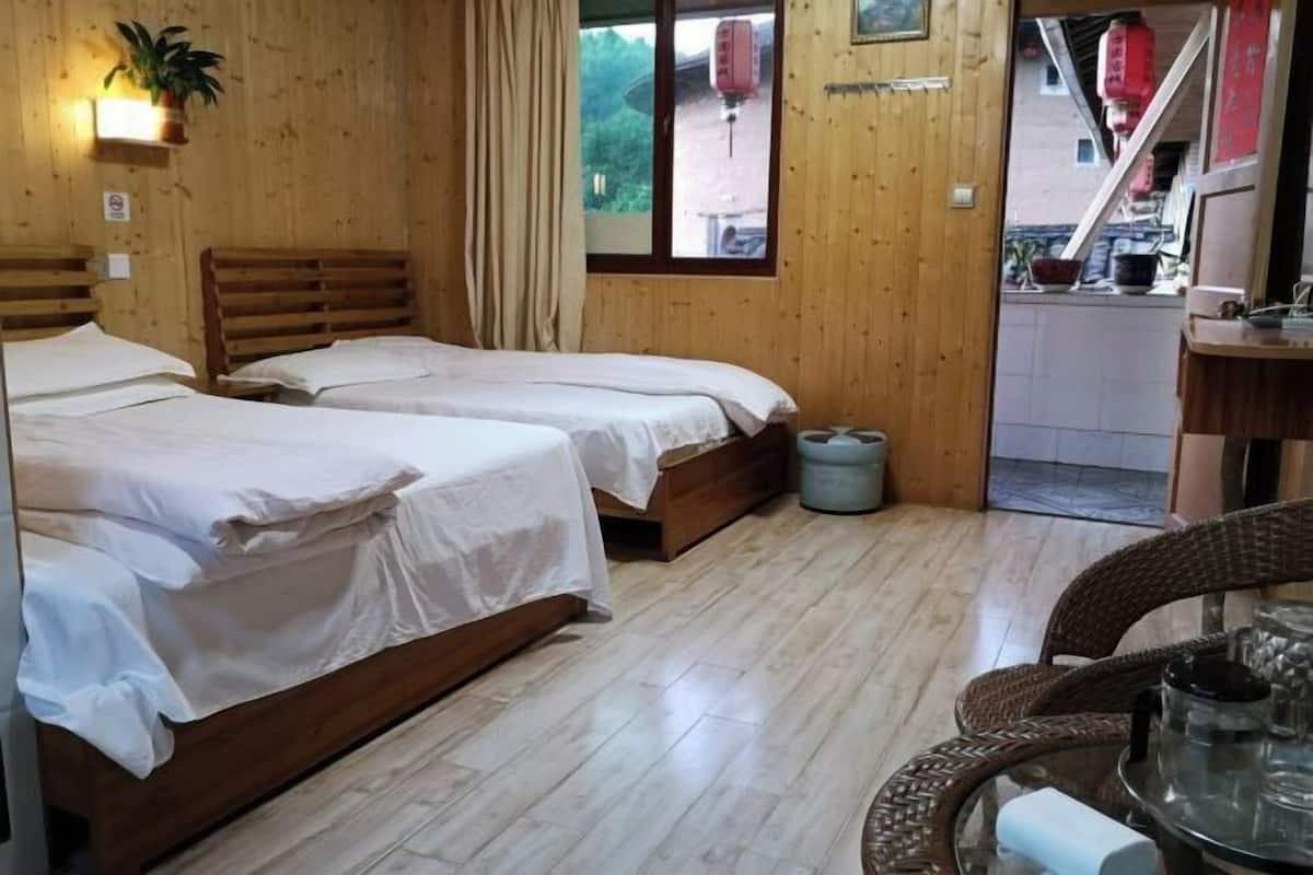 A wooden room with two beds, a small table with a teapot, and a window with a view of the outside.