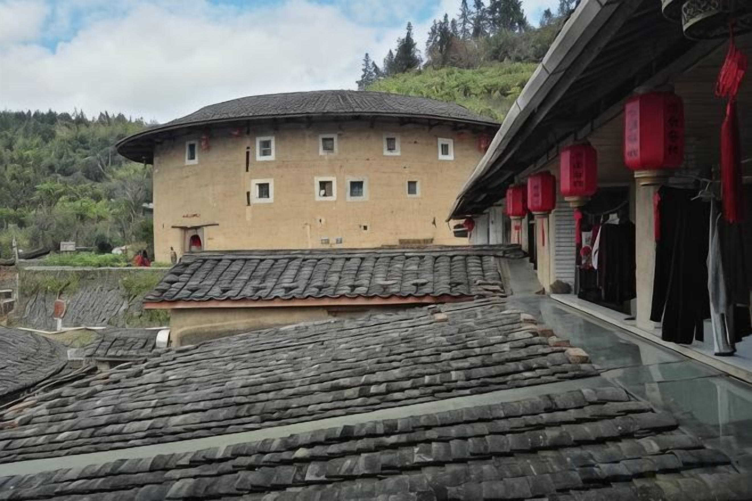 Un edificio tradicional con techo curvo, un balcón con faroles rojos y vistas a tejados escalonados.