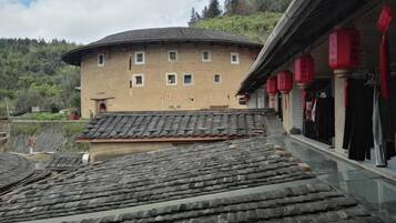 Un edificio tradicional con techo curvo, un balcón con faroles rojos y vistas a tejados escalonados.