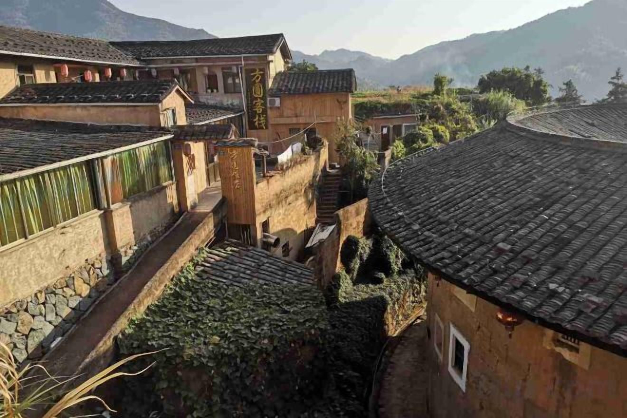 A traditional courtyard with buildings featuring tiled roofs and stone walls.