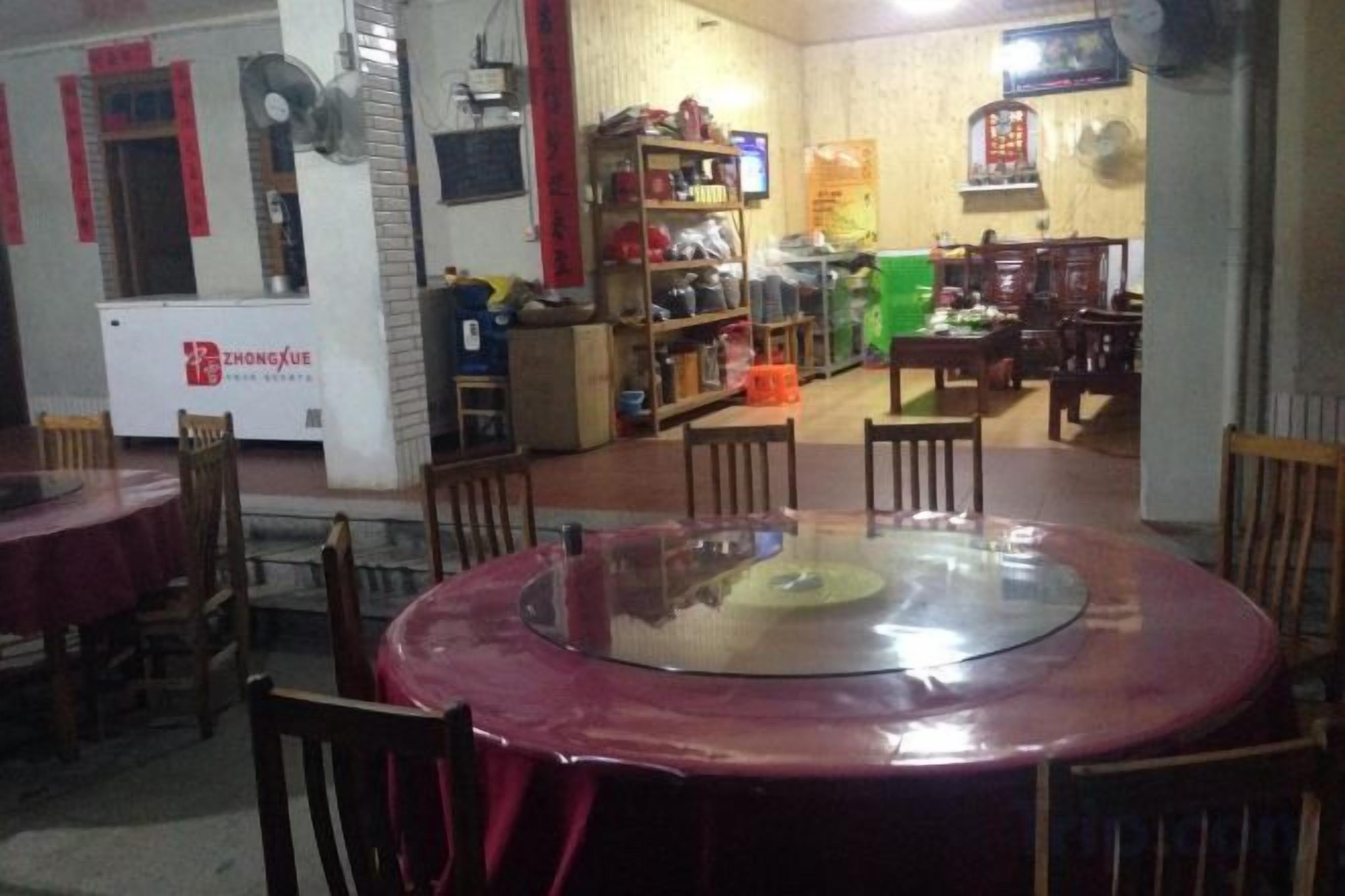 Un comedor con mesas y sillas redondas, una cocina con varios electrodomésticos, y un letrero con texto visible.