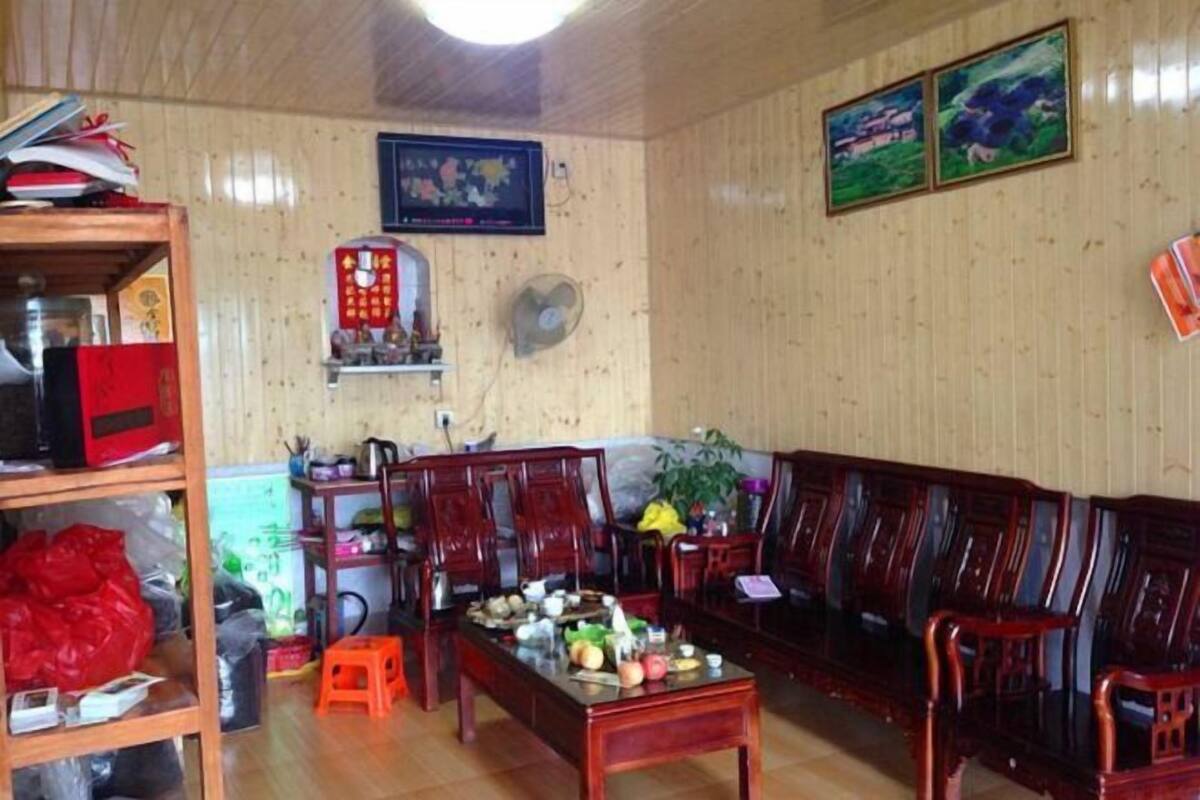 A traditional wooden interior with a sofa, chairs, a small table, and a fan.