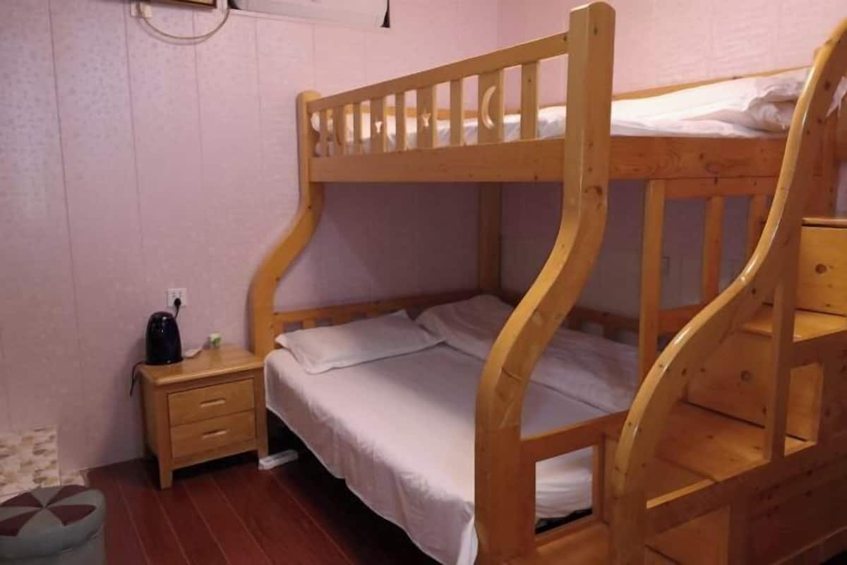 A bunk bed with a wooden frame, a small bedside table, and a pillow.