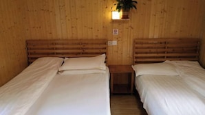 Dos camas individuales con cabeceros de madera en una habitación con paredes de madera y una pequeña mesa entre ellas.