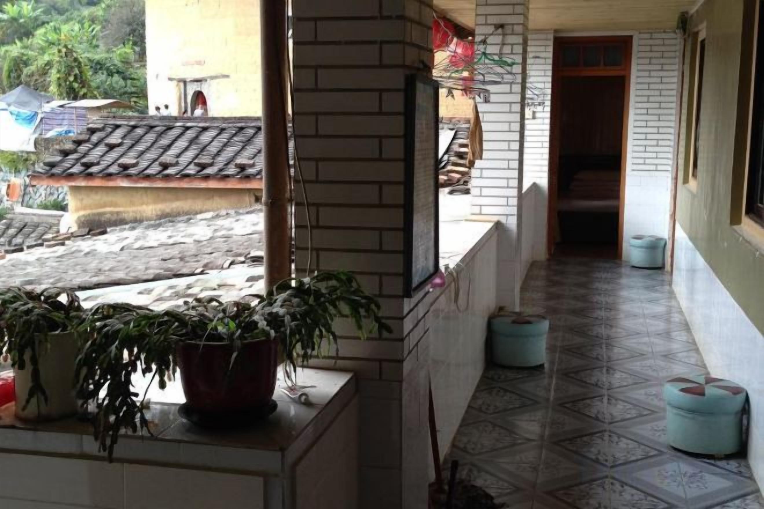 A corridor with tiled flooring, potted plants, and a doorway leading to an interior space.