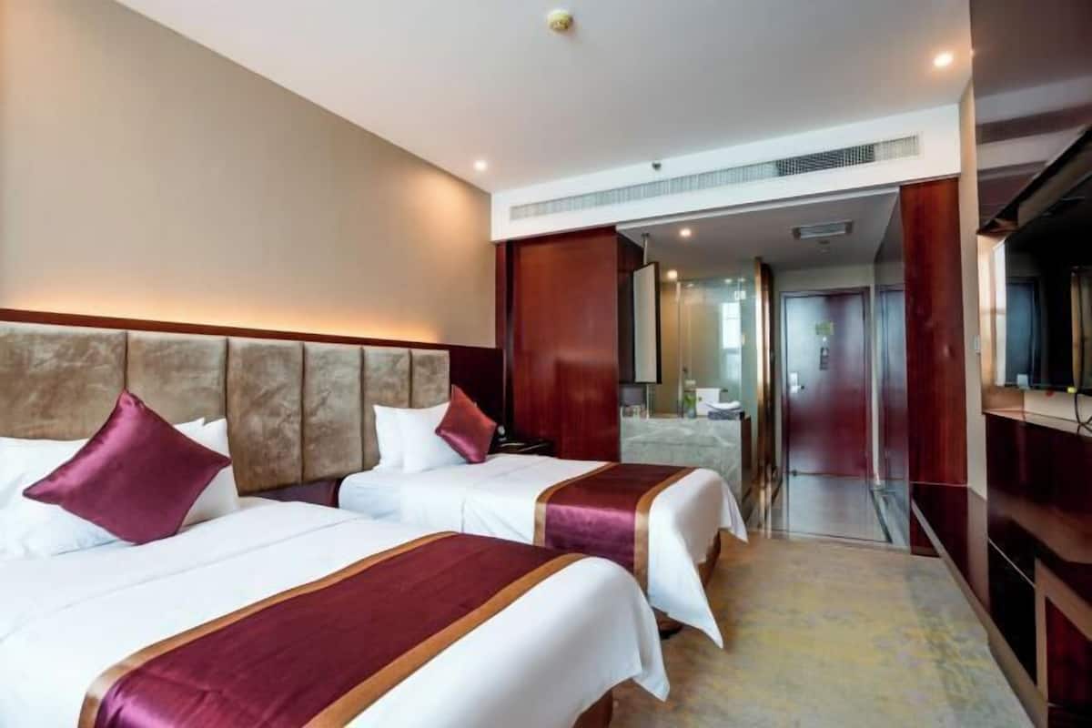 Une chambre d’hôtel avec deux lits, un grand miroir et une vue sur le couloir.