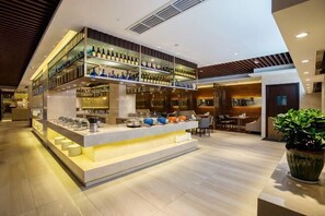A modern bar area with a two-tiered shelf displaying bottles, a counter with bar tools, and a seating area with tables and chairs.