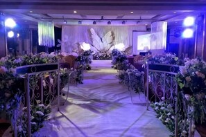 Pasillo decorado con arreglos florales y un escenario al final.