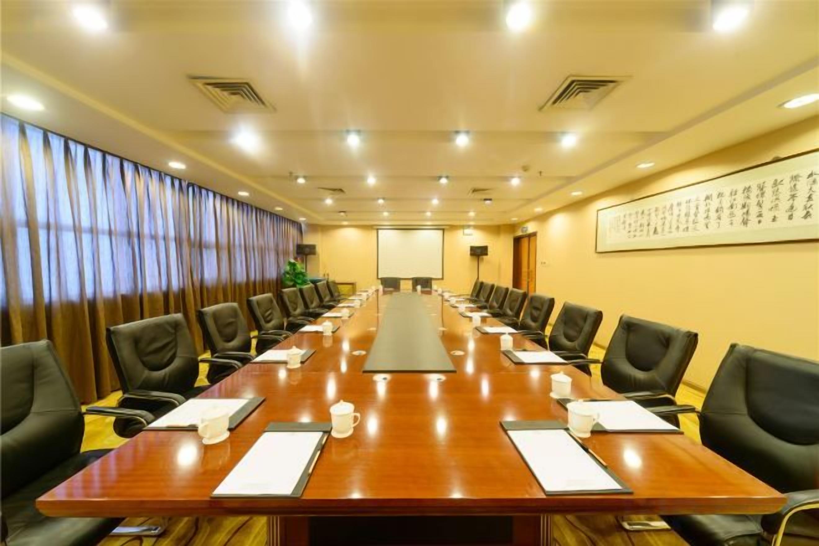 A conference room with a long table, chairs, and a projector screen.