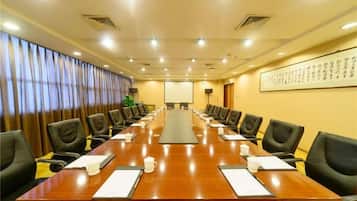 A conference room with a long table, chairs, and a projector screen.