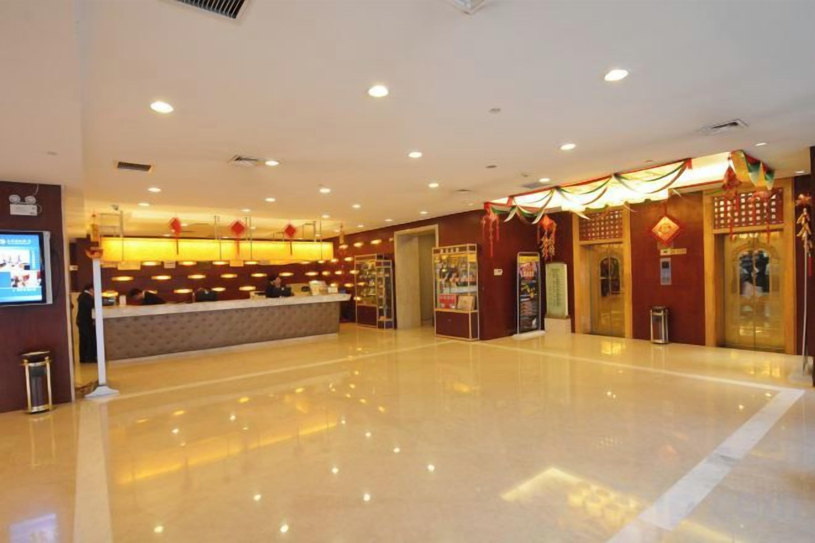 A hotel lobby with a reception desk, a large mirror, and a clean, shiny floor.