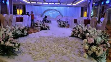 Een bruiloftsdecoratie met een podium, bloemstukken en ronde tafels.