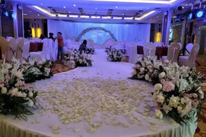 A wedding ceremony setup with a stage, floral arrangements, and round tables. - Dahe International Hotel (Zhengzhou East Railway Station) (Zhengzhou)
